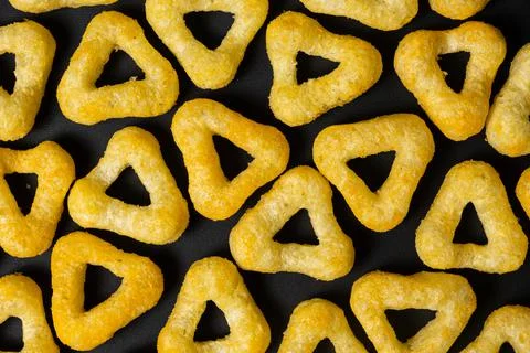 Delicious crispy corn chips triangular shape with spices on a black backgroun 스톡 사진