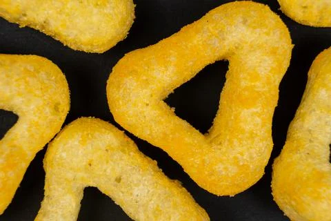 Delicious crispy corn chips triangular shape with spices on a black backgroun 스톡 사진