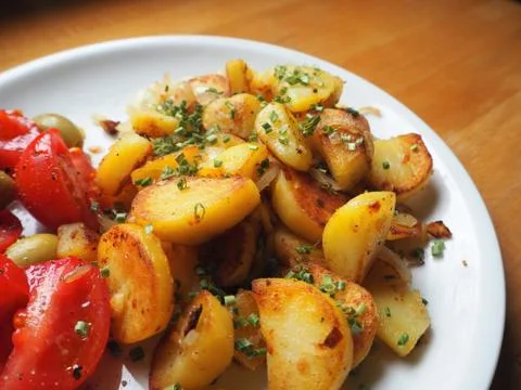 Delicious crispy fried potatoes garnished with chive and tomato Stock Photos