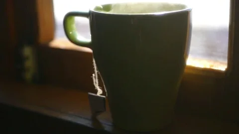 Delicious cup of hot tea standing on the window sill near the window, with Stock Footage 73115352