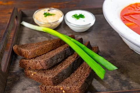 Delicious dark rye bread served with dips and green onion garnish Stock Photos