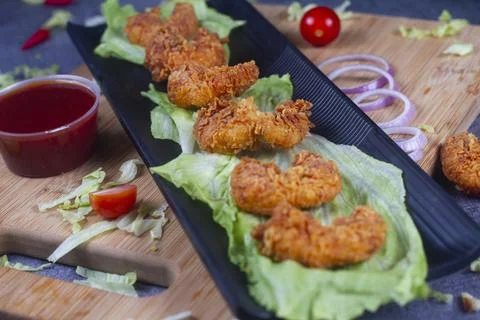 Delicious deep fried breaded cheese prawn on black plate on wooden table. sel Stock-Fotos