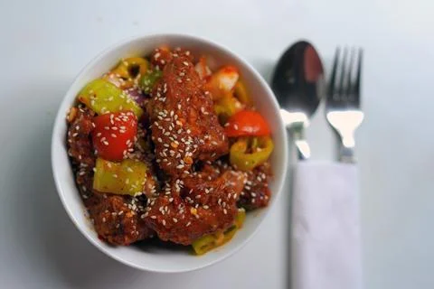 Delicious Devil Chicken Dish Presented in White Bowl with Cutlery. Stock Photos