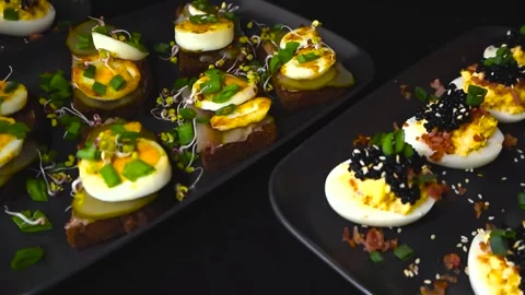 Delicious Deviled Eggs With Caviar and Rye Bread Canapes Rotating on Plates Stock Footage 336316669