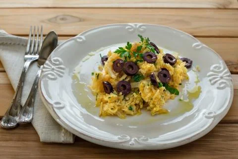 A delicious dish of shredded cod, with potato straw, mixed egg and dark olive Foto stock