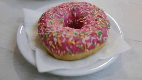 Delicious donuts lying on the plate closeup. The bun is glazed and sprinkled. Si Stock Footage 85102663