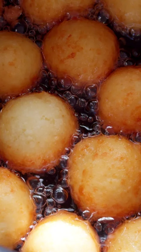 Delicious donuts with no central hole are turning gold in the boiling oil.  Stock Footage 279486162