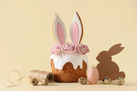 Delicious Easter cake with bunny ears, threads, candle and eggs on beige back Stock Photos