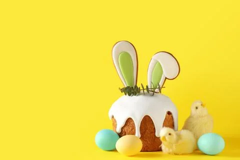 Delicious Easter cake with bunny ears, chickens and eggs on yellow background Stock Photos
