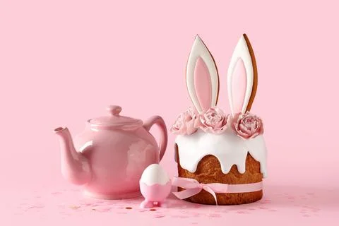 Delicious Easter cake with bunny ears, teapot and egg on pink background Stock Photos
