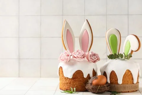 Delicious Easter cakes with bunny ears, roses, leaves and egg on white tile b Stock-Fotos