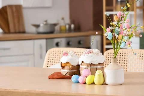Delicious Easter cakes with painted eggs and vase of decorative bouquet on ta Stock Photos