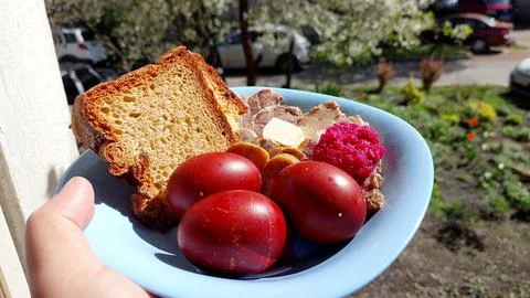 Delicious Easter plate with red eggs, bread, and meat in springtime setting Stock Photos
