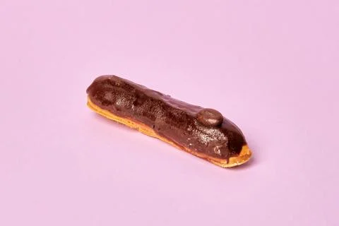 Delicious Eclair covered with chocolate icing. Isolated on a pink background. Stock Photos