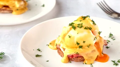 Delicious eggs benedict with bacon, hollandaise sauce and herbs. Video stock 131193791