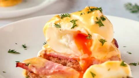 Delicious eggs Benedict with bacon, hollandaise sauce and herbs. Video stock 131327072