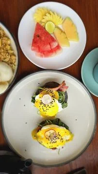 Delicious Eggs Benedict Breakfast with Fresh Fruit Platter Stock Photos