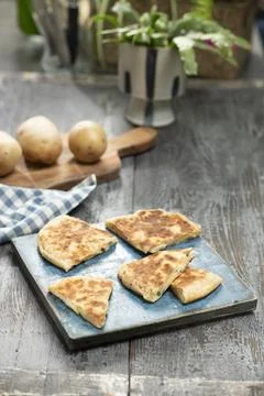 Delicious flatbread with potatoes and cheese, served on the table. Stock Photos