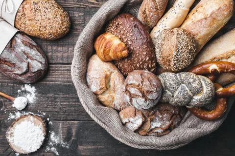 Delicious fresh bread inside a sack on wooden background Stock Photos