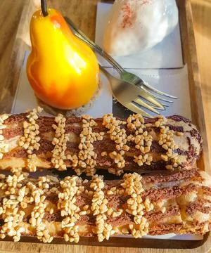 Delicious fresh cakes eclairs and dessert in the shape of a pear on a wooden  Stock Photos