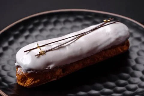 Delicious fresh profiterole or eclair with chocolate on a black ceramic plate Stock Photos