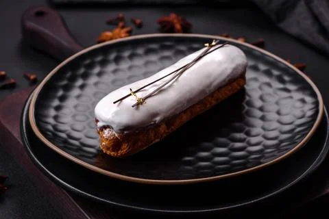 Delicious fresh profiterole or eclair with chocolate on a black ceramic plate Stock Photos