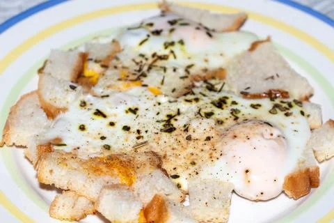 Delicious fried eggs on toasted bread with herbs and spices served 스톡 사진
