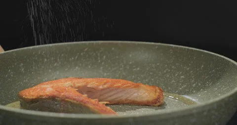 Delicious fried fish on black background. Red salmon fish on a frying pan. Slow Stock-Footage 252699766
