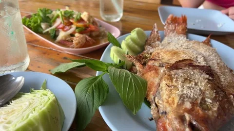 Delicious fried fish or fish fry on a black plate with onion, tomato, and lemon Vídeo Stock 316245848