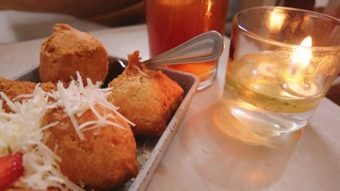 Delicious fried snacks served on a plate with grated cheese and a lit candle on  库存影片 343401774