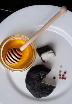 Delicious goat cheese covered with black ash and honey Stock Photos