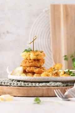 Delicious golden crispy cod fish fritters stacked on a rustic plate with fr.. Stock Photos