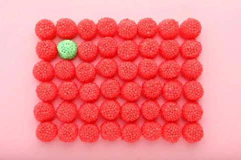 Delicious green gummy raspberry candy among red ones on pink background, flat 스톡 사진