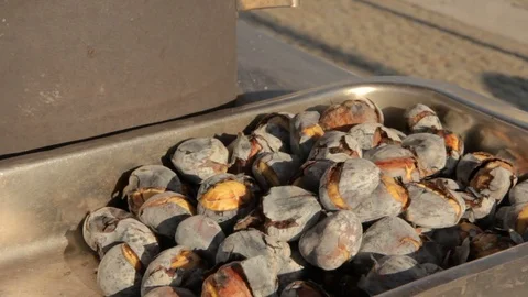 Delicious grilled chestnuts on the street on rustic tray in hands Stock Footage 80438418