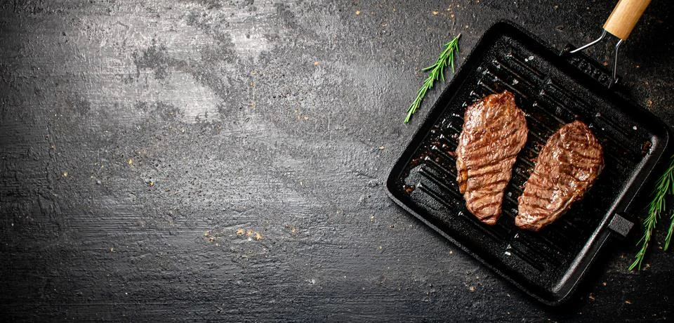 Delicious grilled steak in a frying pan. Stock Photos