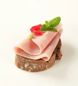 Delicious ham slice on dark bread with garnish Stock Photos