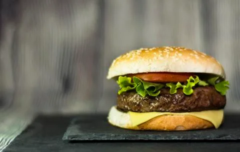 Delicious hamburger with cheese, lettuce and tomato on a stone Stock Photos
