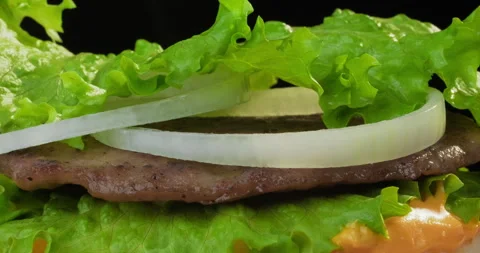 Delicious hamburger or cheeseburger preparation. Lettuce falling on a bun with Stock Footage 293544160