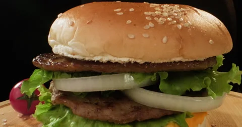 Delicious hamburger or cheeseburger preparation. Half of bun with sesame falling Stock Footage 293545612