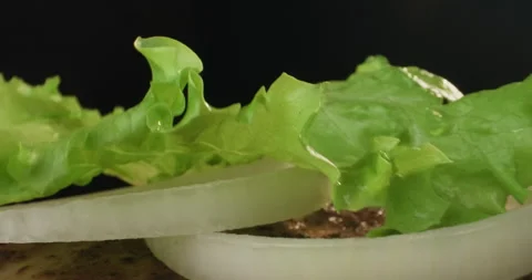Delicious hamburger preparation. Chef putting lettuce on a bun with grilled Stock Footage 296094705