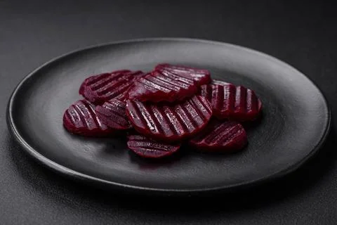Delicious healthy boiled ruby-colored beets sliced ??on a black plate Stock Photos