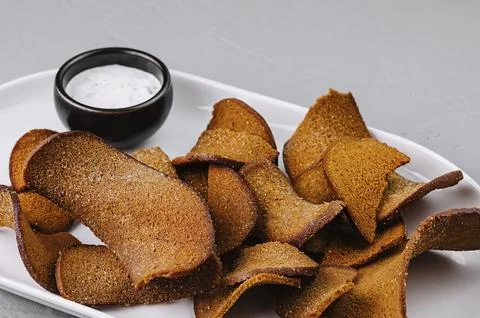Delicious homemade bread chips served with a creamy dipping sauce on a modern Stock Photos