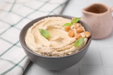 Delicious hummus with chickpeas served on white tiled table, closeup Stock Photos