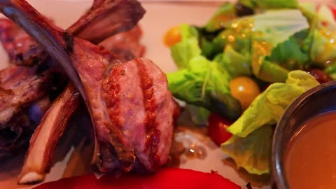 Delicious lamb chops served with roasted red pepper and fresh green salad. 库存影片 339207646