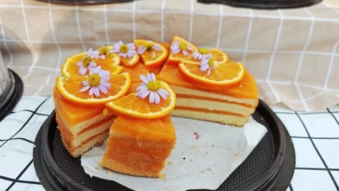 Delicious layered orange cake decorated with fresh orange slices and flowers. 스톡 동영상 339780596