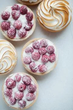 Delicious lemon and raspberry tartlets with meringue on a white vintage plate Stock Photos