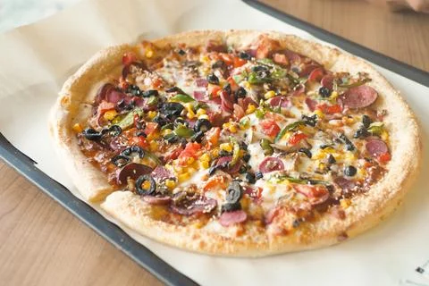 A Delicious Loaded Pizza with an Array of Toppings on a Wooden Table Stock Photos