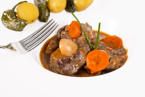 A delicious looking beef stew with a fork and out of focus vegetables. homema Stock Photos