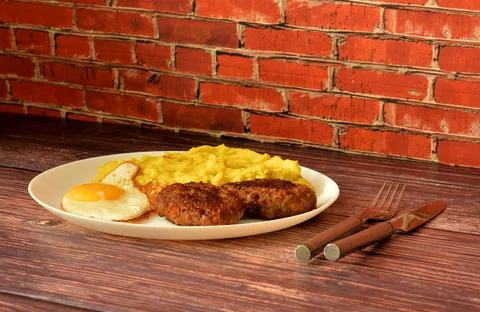 Delicious lunch, a plate of mashed potatoes with a fried egg and two meat c.. Fotos Stock