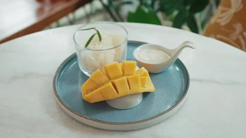 Delicious Mango Sticky Rice Served on a Round Plate With Coconut Sauce and a Stock Footage 312707073